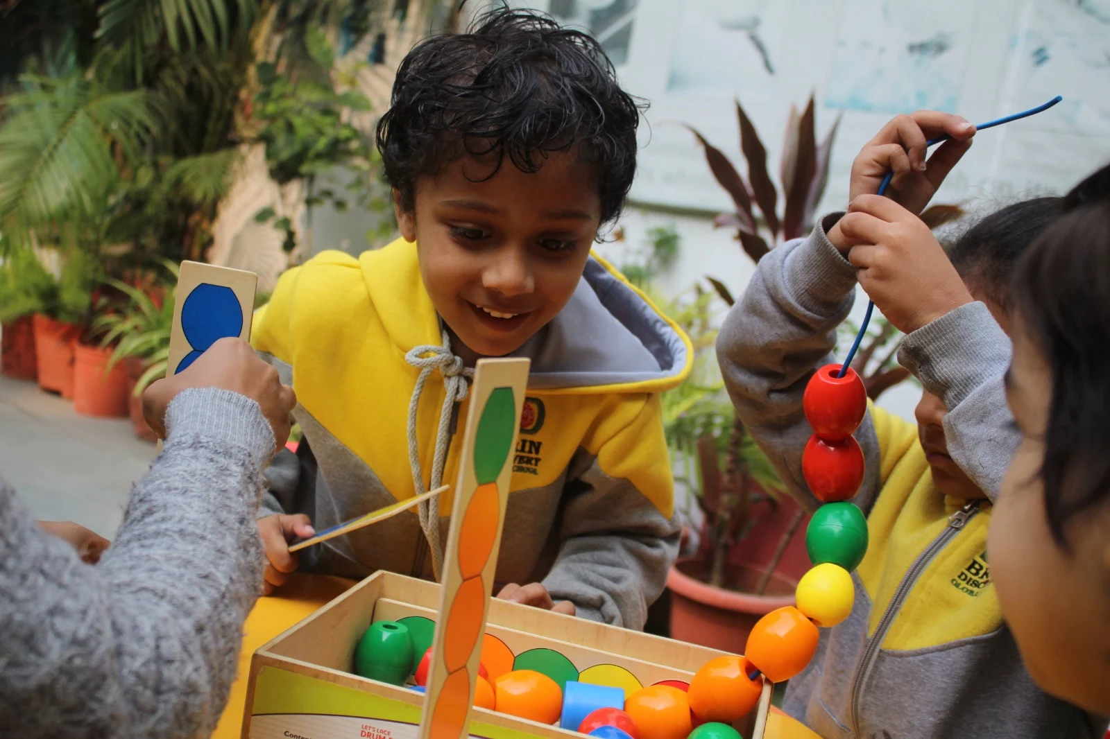 Children practising threading and counting with colourful beads