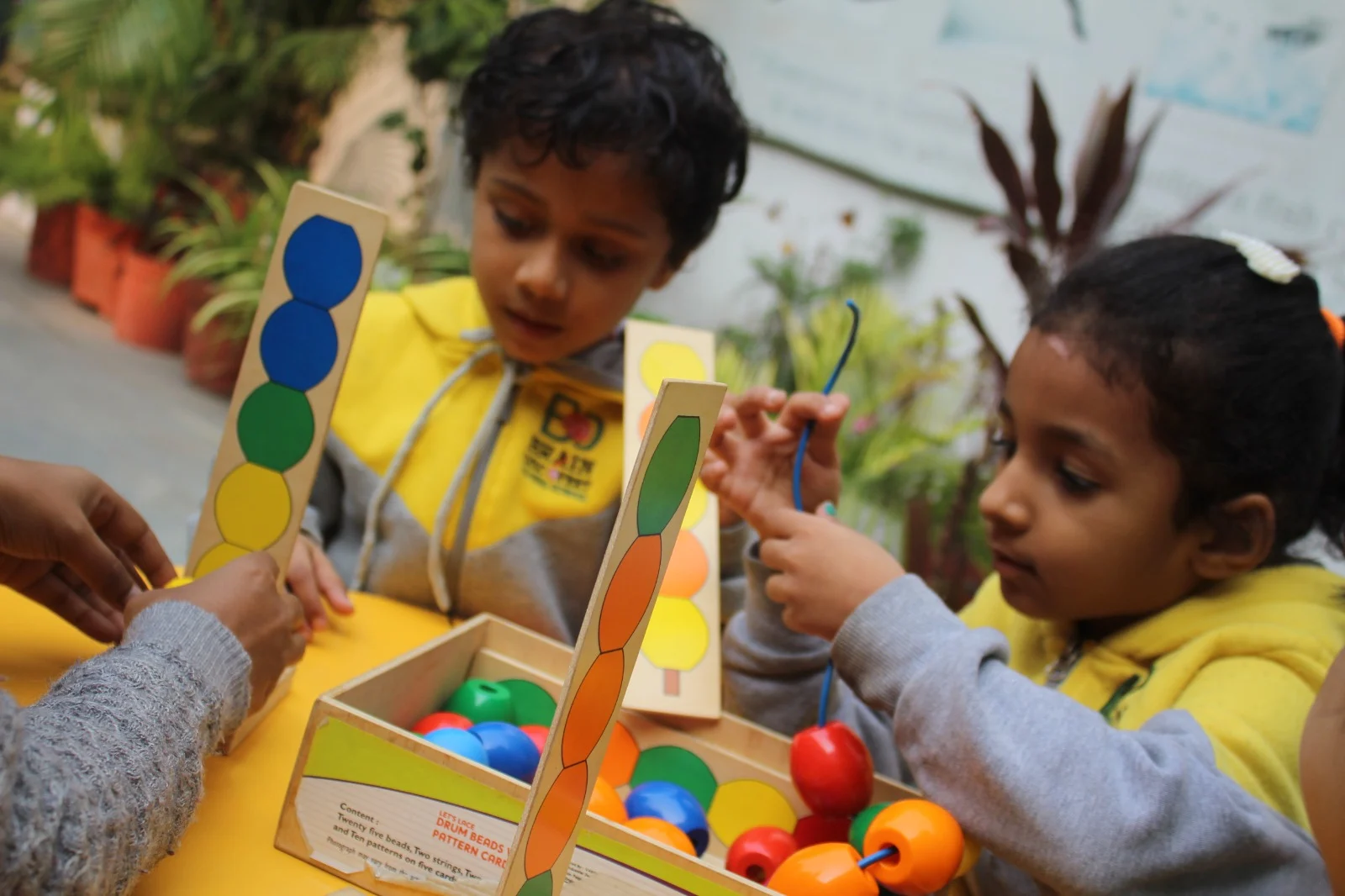 Children learning colours and patterns with threading beads