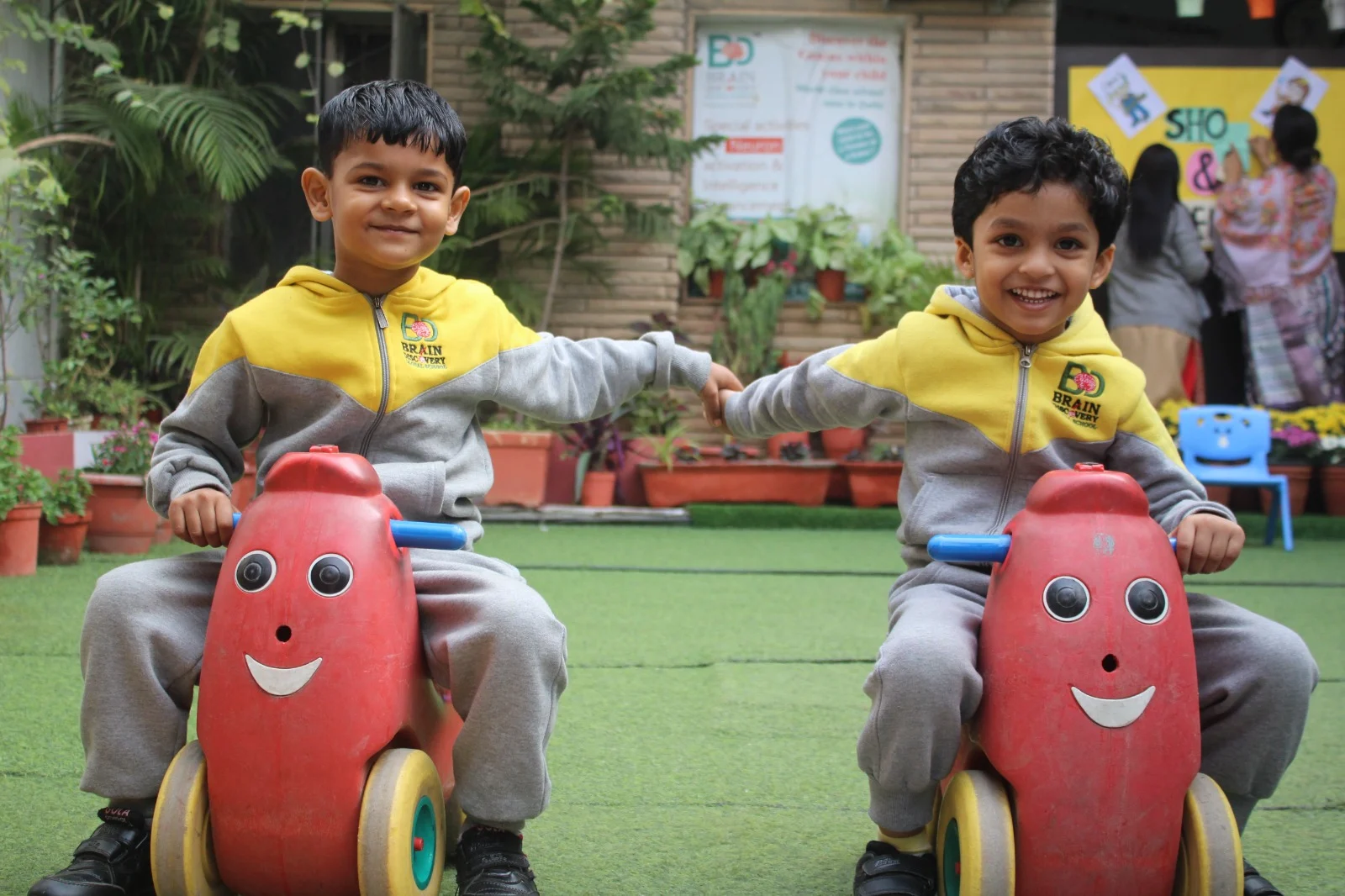 Two students enjoying ride-on toys in the school playground